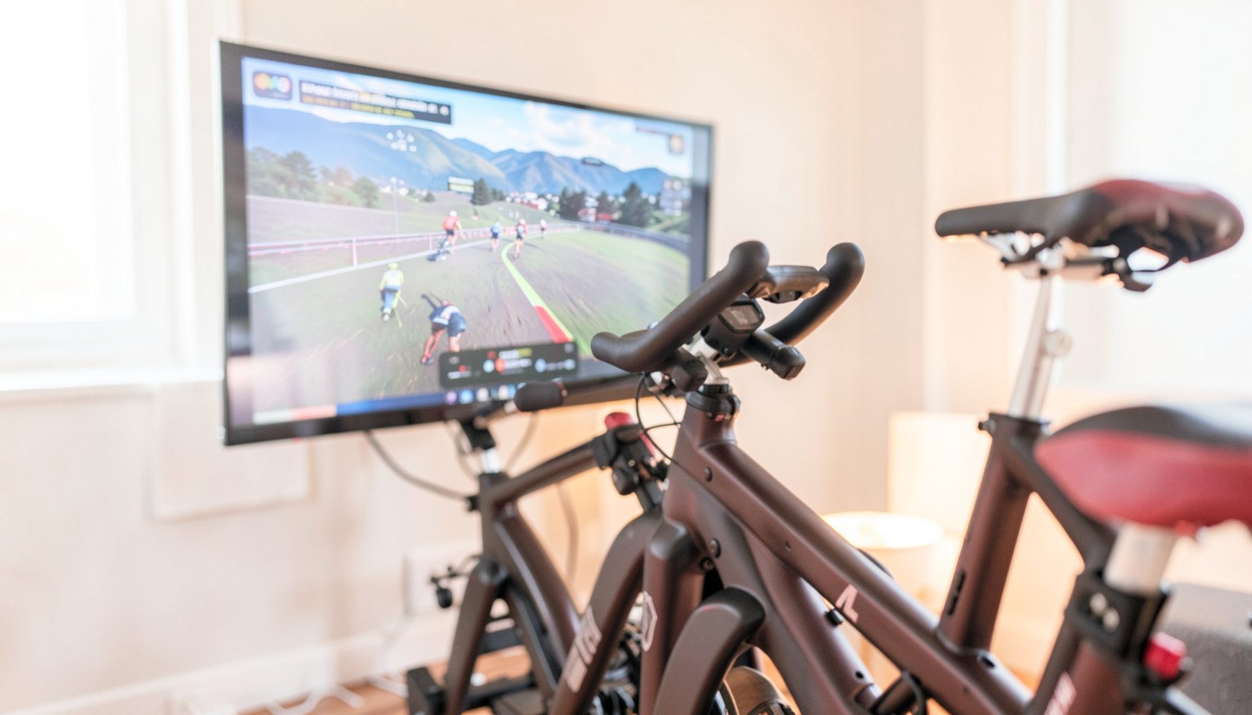 Indoor cycling setup with a trainer and screen displaying a Zwift race course, warm ambient lighting, deep focus on the bike